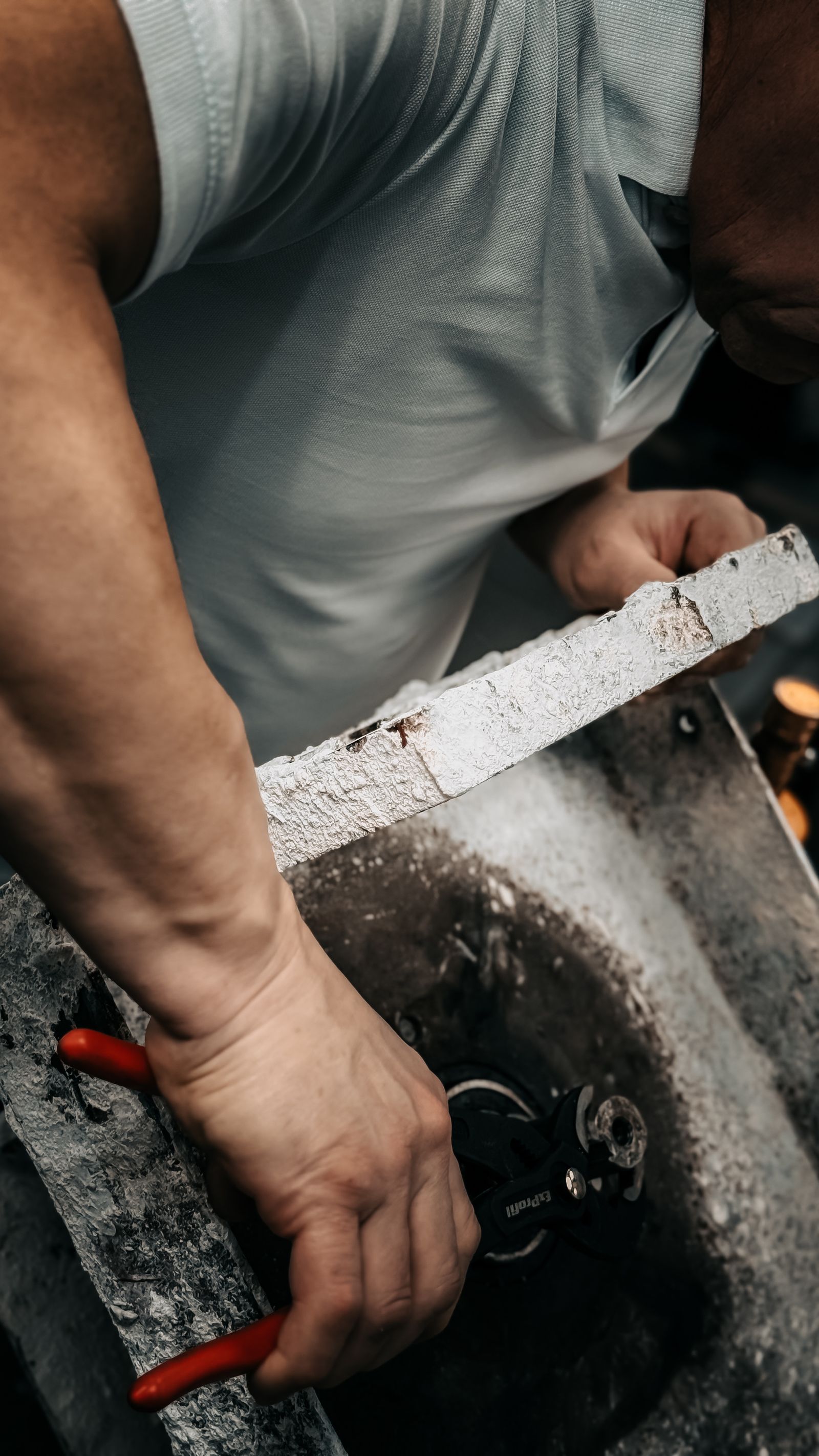 Close-up of a tradesperson's hands working on a mechanical part with hand tools