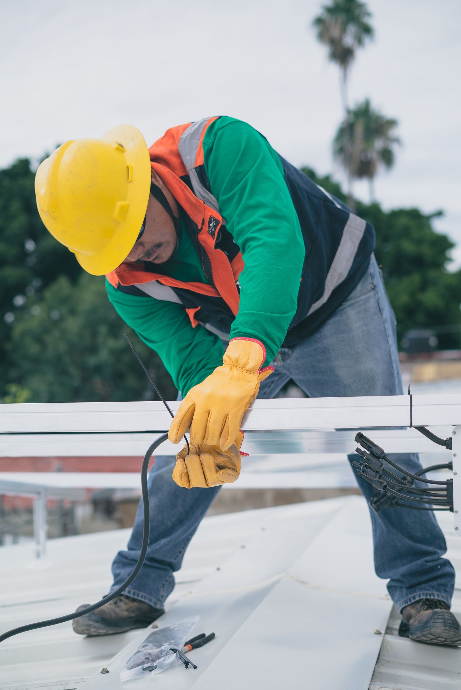 A worker in safety gear installing equipment on a roof