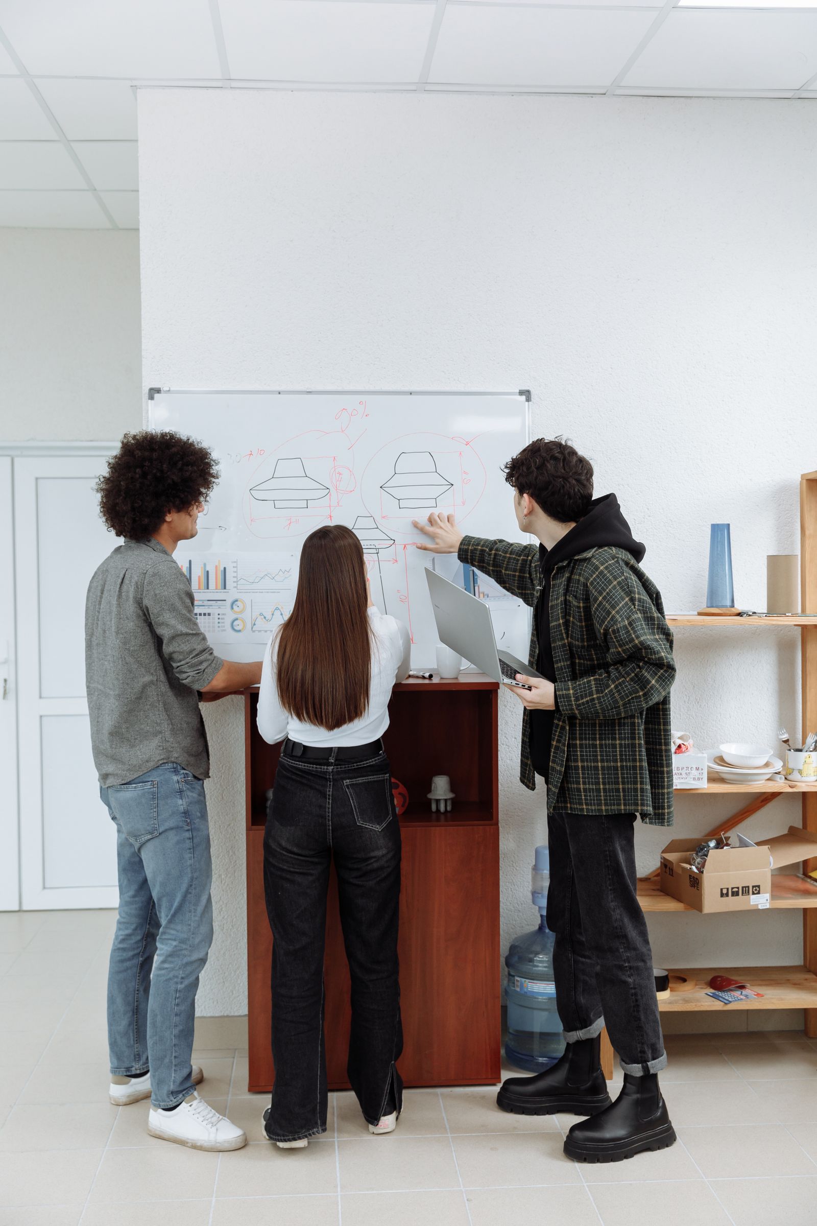 Three people planning at a whiteboard in an office