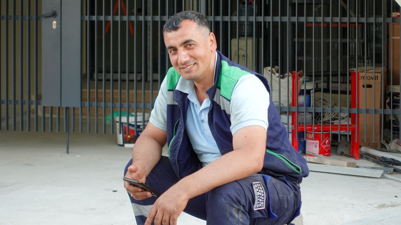 A tradesperson in work clothes checking a phone on site