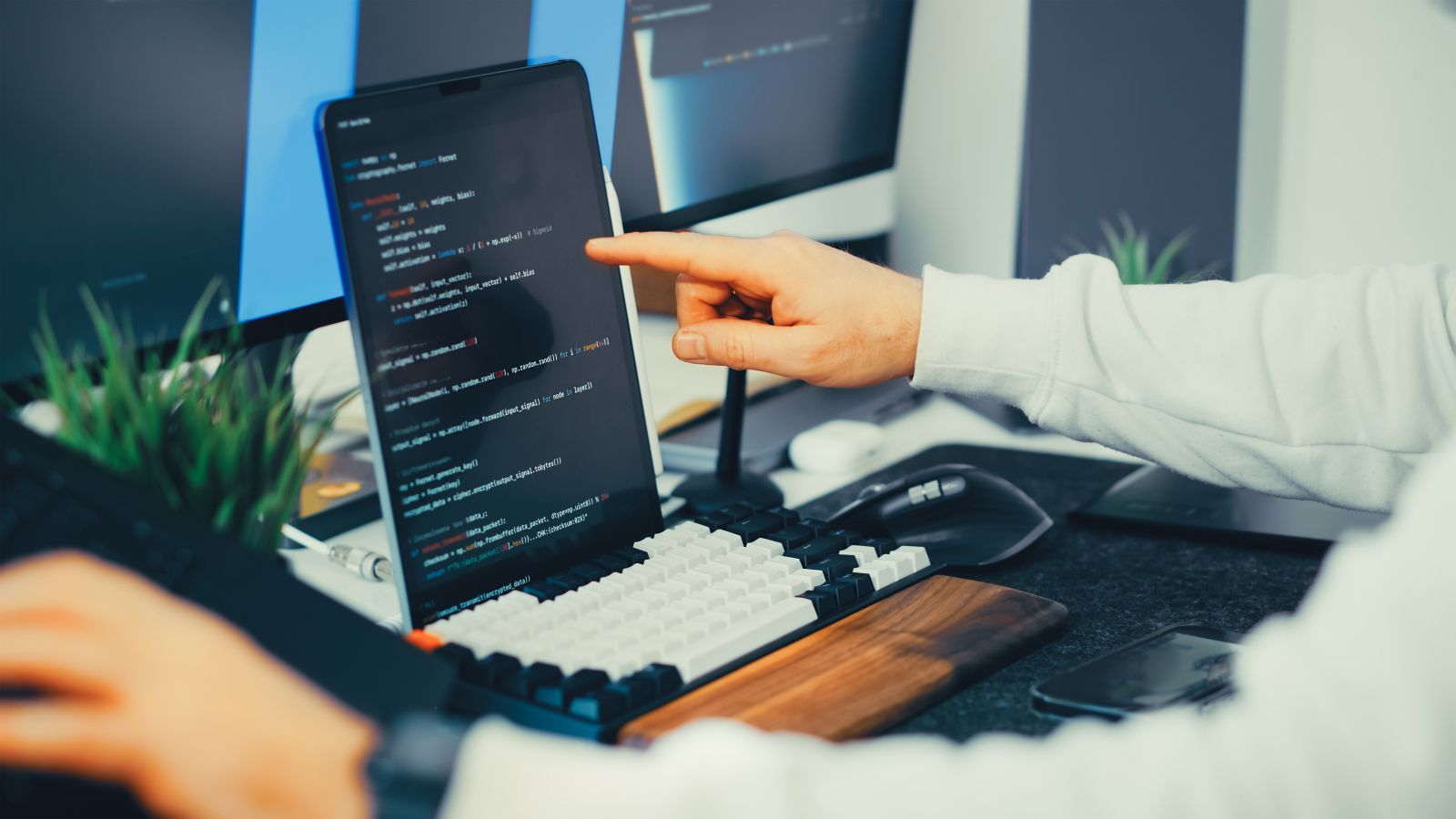 A developer pointing at code on a laptop screen